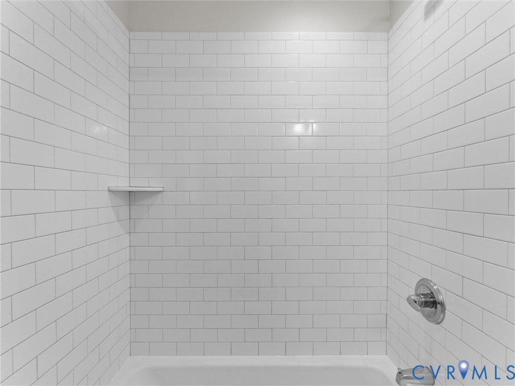 White subway tile shower surround with an integrated corner shelf and chrome fixtures