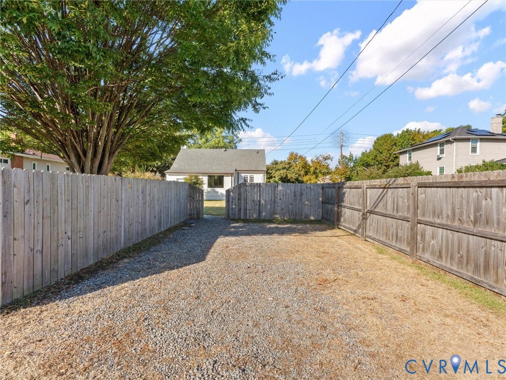 Gravel driveway with wood privacy fencing and a rear access gate