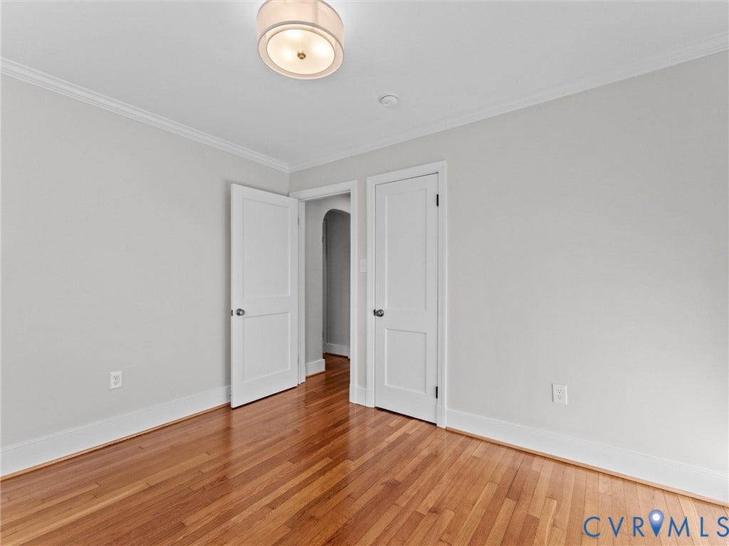 Hardwood flooring, painted walls, crown molding, white trim, and a ceiling-mounted light fixture