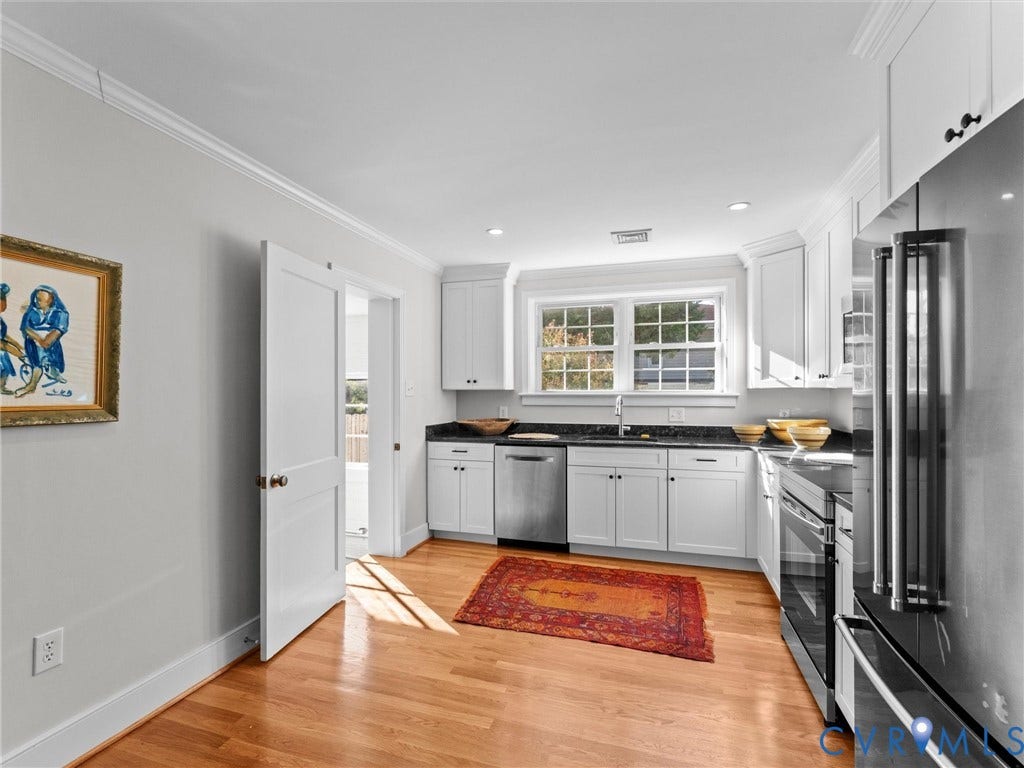 White kitchen cabinetry, dark countertops, hardwood flooring, stainless steel appliances, and recessed lighting