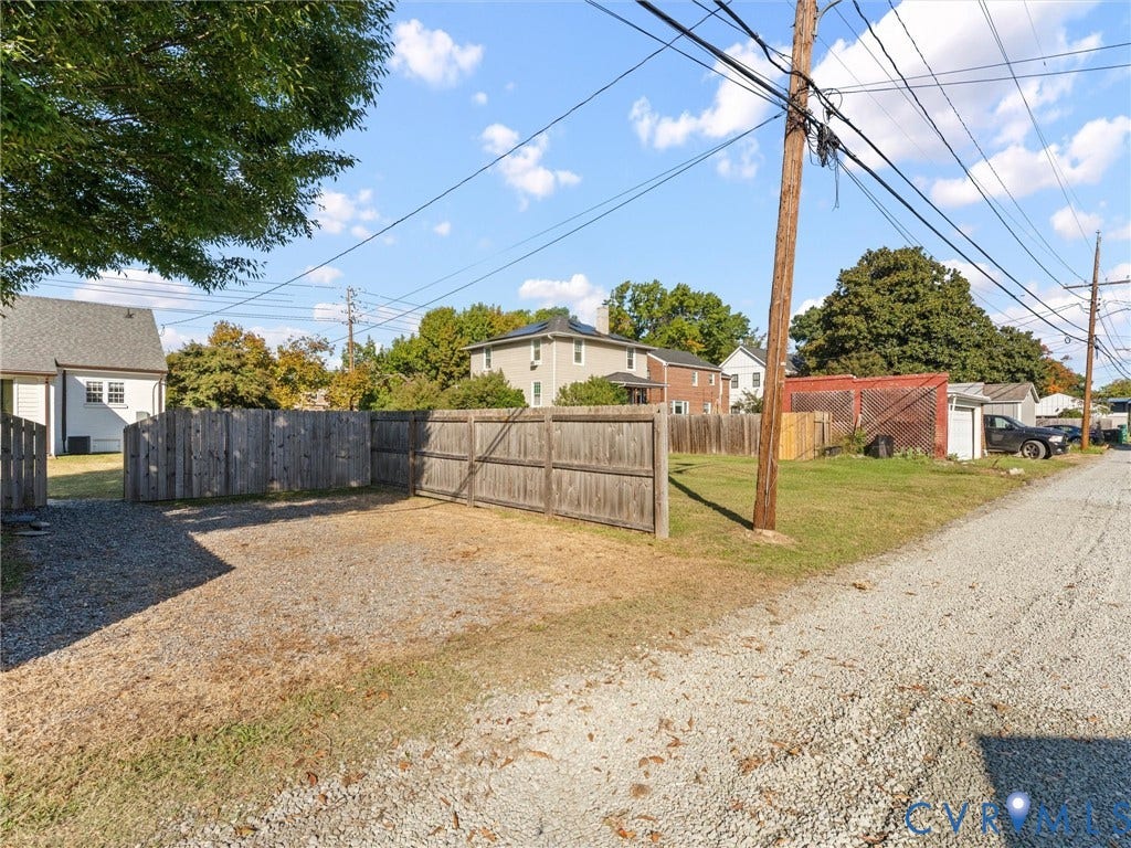 Gravel lot with wood fencing and mature trees