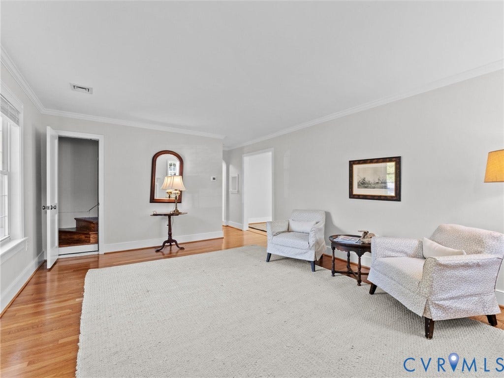 Hardwood flooring, crown molding, white walls, and a visible staircase
