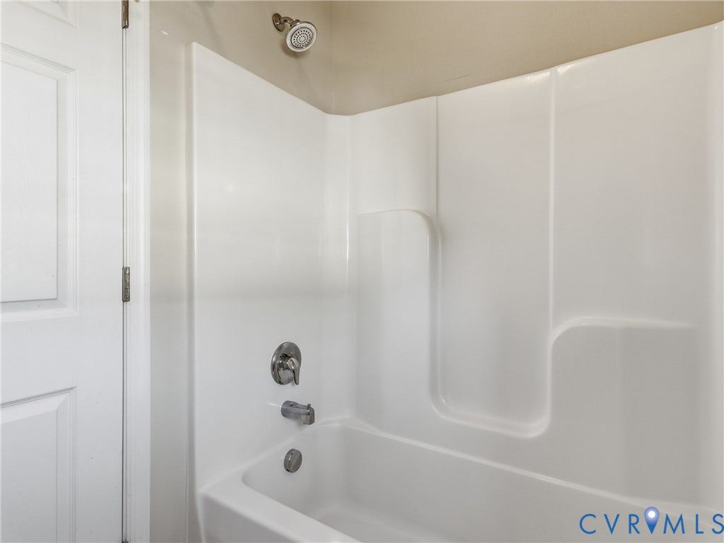 11037 Vogel Court, Bellshire, North Chesterfield, VA 23236 Bathtub and shower combination featuring white molded wall surrounds, a chrome single-handle mixing valve, a chrome diverter spout, and a circular chrome showerhead