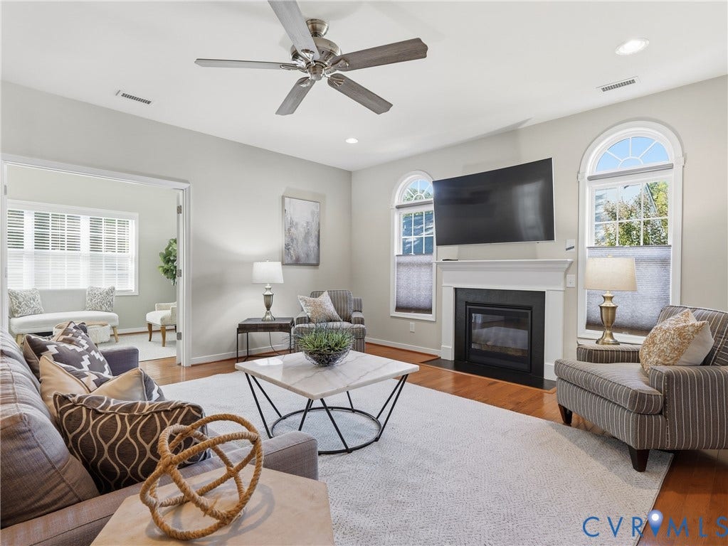11037 Vogel Court, Bellshire, North Chesterfield, VA 23236 Living room featuring wood-finish flooring, a fireplace with a white mantel, arched windows, and a ceiling fan