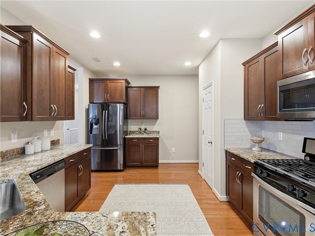 11037 Vogel Court, Bellshire, North Chesterfield, VA 23236 Kitchen featuring dark wood cabinetry, stone-surface countertops, subway tile backsplash, stainless steel appliances, and wood-finish flooring