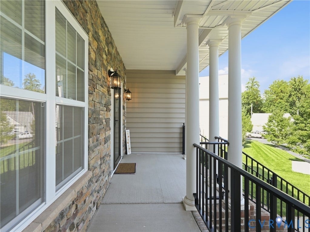 11037 Vogel Court, Bellshire, North Chesterfield, VA 23236 Covered front porch featuring a stacked stone facade, horizontal siding, classic white columns, and black metal railings
