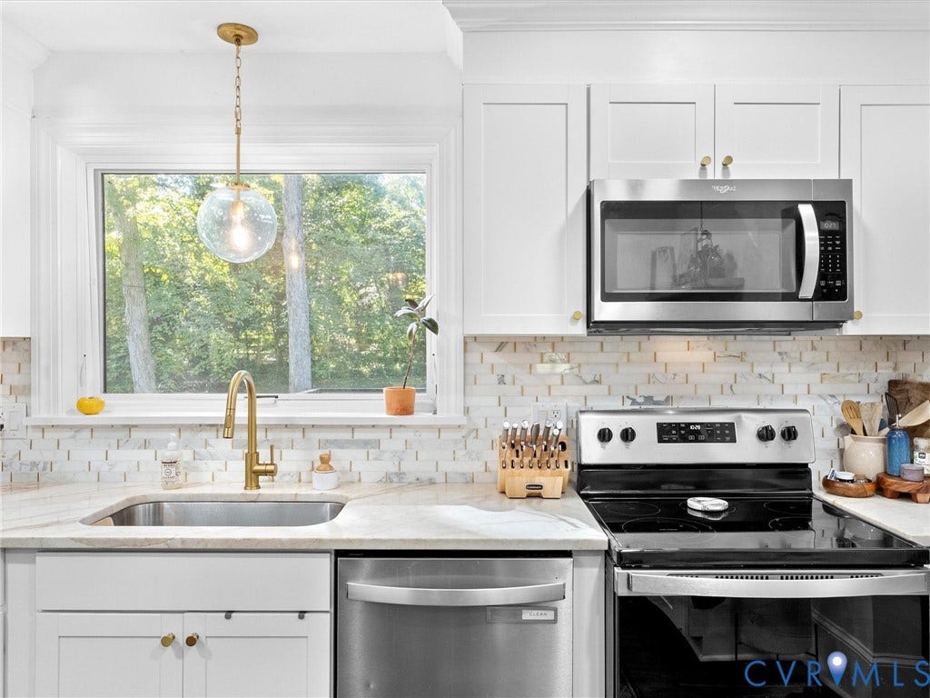 8341 Charlise Road, Stratford Hills, Midlothian, VA 23235 White cabinetry featuring brass hardware, brick-pattern backsplash, stainless steel appliances, brass pull-down faucet, and a globe-style pendant light