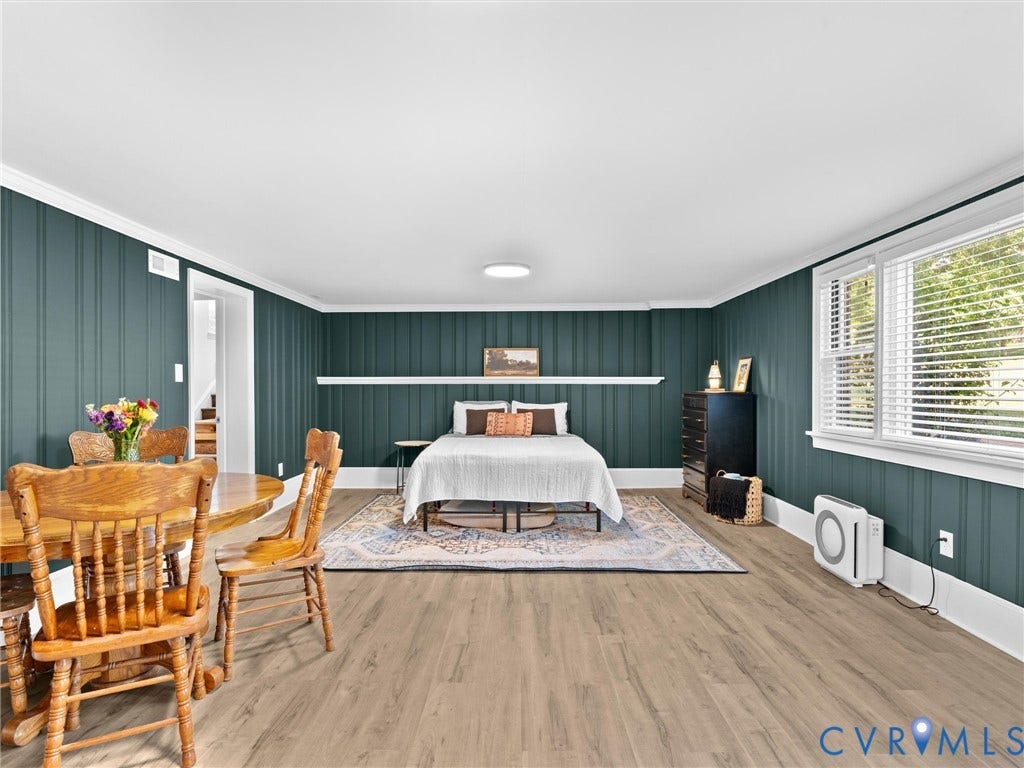8341 Charlise Road, Stratford Hills, Midlothian, VA 23235 Deep teal vertical board-and-batten wall paneling featuring a horizontal chair rail shelf, wood-finish flooring, and large multi-pane windows with horizontal blinds