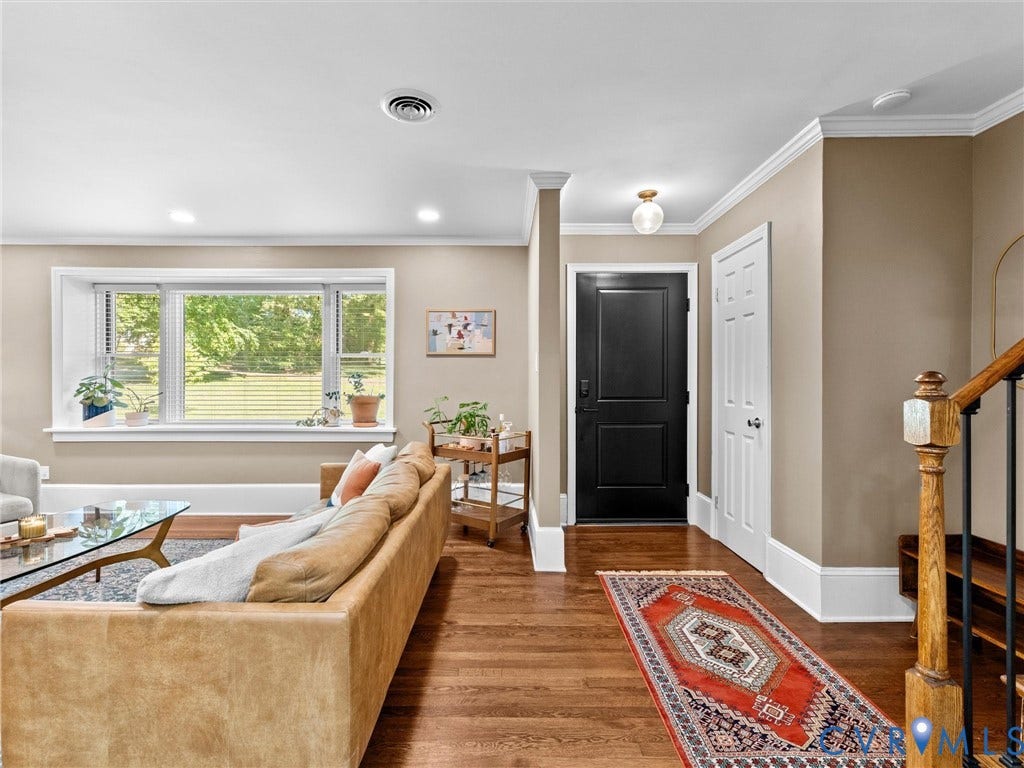 8341 Charlise Road, Stratford Hills, Midlothian, VA 23235 Living area featuring wood-finish flooring, a large bay window, crown molding, a solid-panel door, and a wooden handrail with balusters