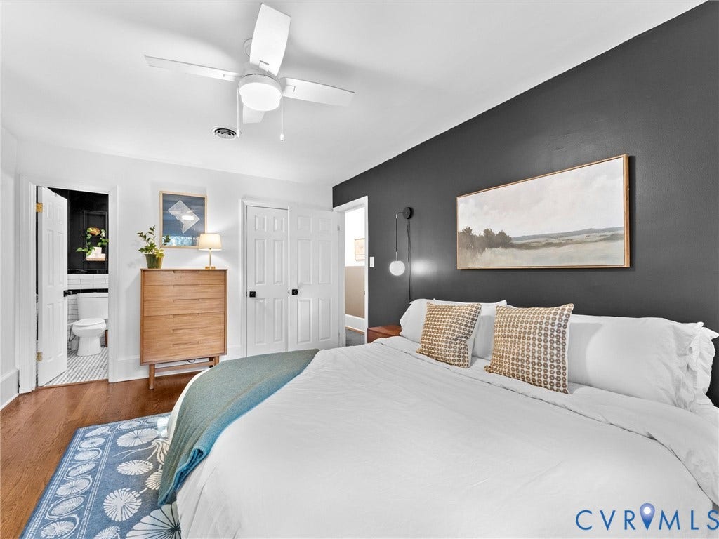 8341 Charlise Road, Stratford Hills, Midlothian, VA 23235 Bedroom featuring wood-finish flooring, a matte dark accent wall, white-paneled closet doors, and a ceiling-mounted light fixture with an integrated fan