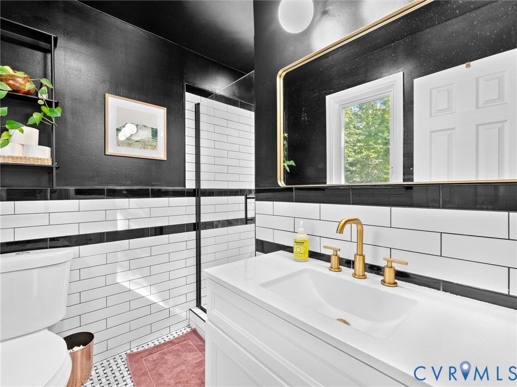 8341 Charlise Road, Stratford Hills, Midlothian, VA 23235 White vanity with a rectangular sink, brushed gold widespread faucet, rectangular mirror with metallic framing, and white and black subway tile wainscoting