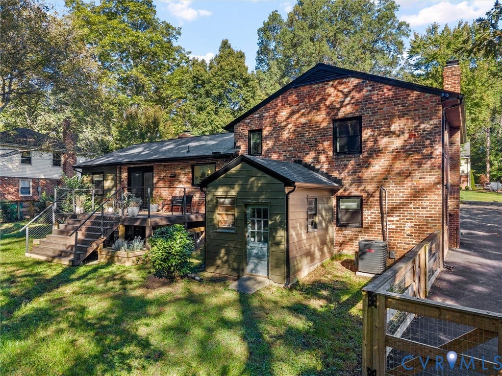 8341 Charlise Road, Stratford Hills, Midlothian, VA 23235 Brick Colonial home featuring a covered front porch with wooden railings, expansive rear deck with multi-level wooden construction, mature landscaping with established trees throughout the grounds, and a detached outbuilding
