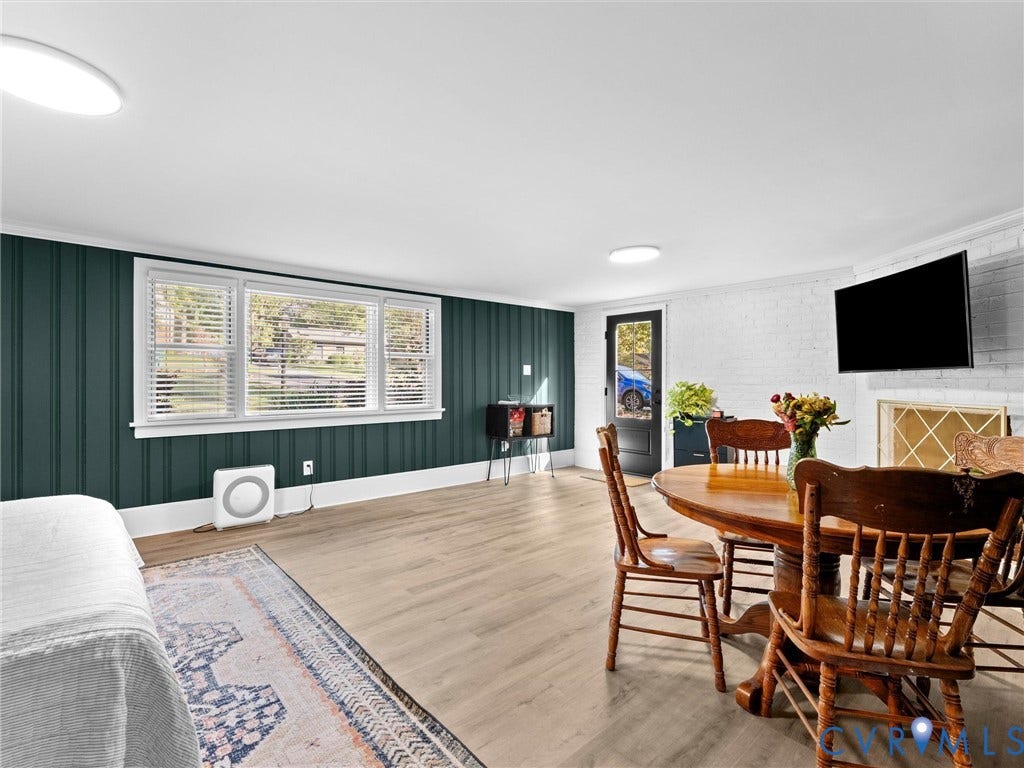 8341 Charlise Road, Stratford Hills, Midlothian, VA 23235 Interior space featuring wood-finish flooring, vertical paneling, large picture windows, a painted brick fireplace, and a glass-paneled exterior door