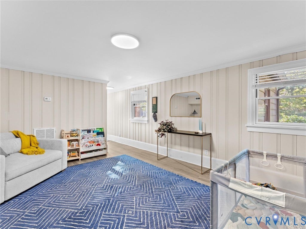 8341 Charlise Road, Stratford Hills, Midlothian, VA 23235 Interior space featuring vertical wood-plank wall paneling, light-tone wood-finish flooring, two double-hung windows, and flush-mount circular overhead lighting
