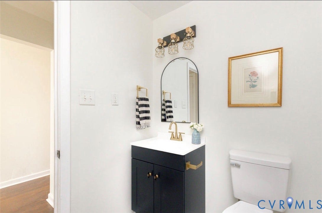 2211 Apollo Road, Fairfield, VA 23223 Vanity with white countertop, arched mirror, brass-finish faucet, and overhead three-light fixture