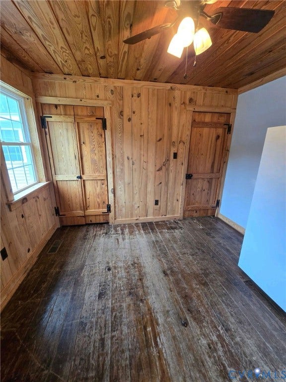 Wood-paneled walls and ceiling, wood-finish flooring, two wood-paneled doors with black hardware, and a ceiling fan with integrated lighting