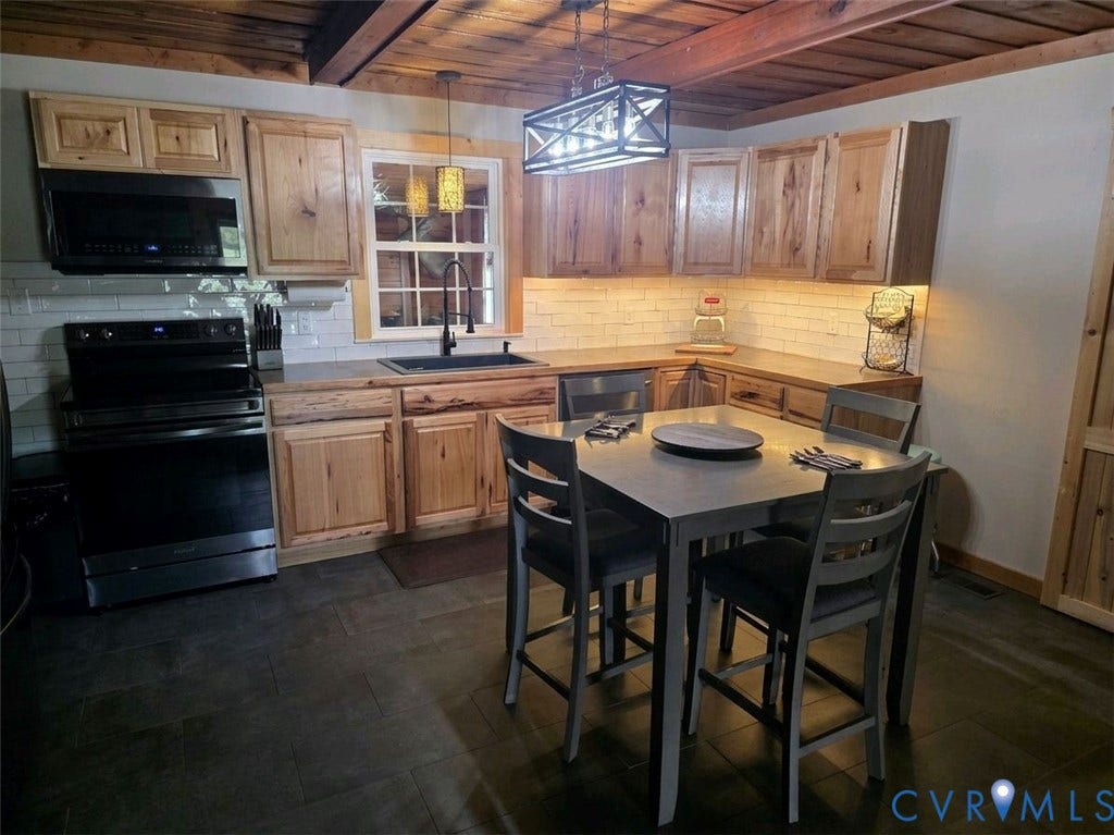 Wood ceiling with exposed beams, wood-finish cabinetry, dark flooring, white subway tile backsplash, and black stainless steel appliances