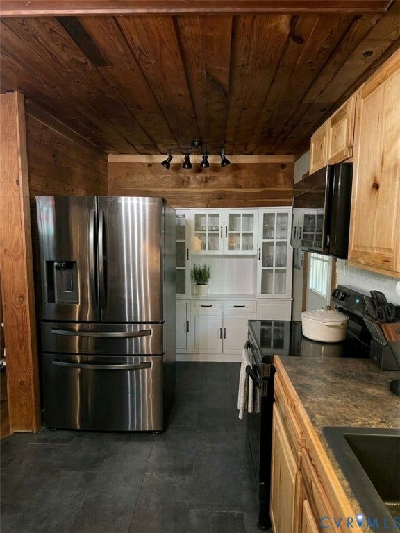 Wood-paneled ceilings, white built-in cabinetry with glass inserts, stainless steel refrigerator, and dark stone-look flooring