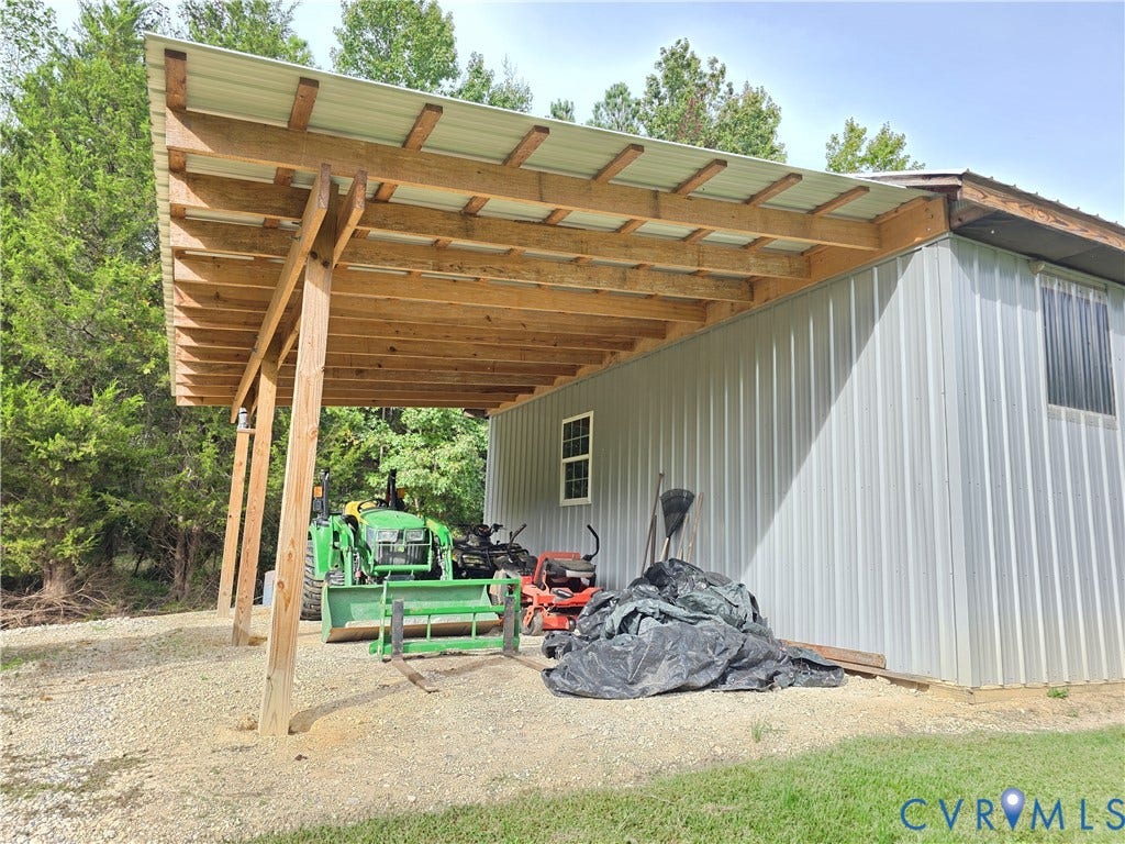 Attached carport structure with wood beam framing and a corrugated metal roof