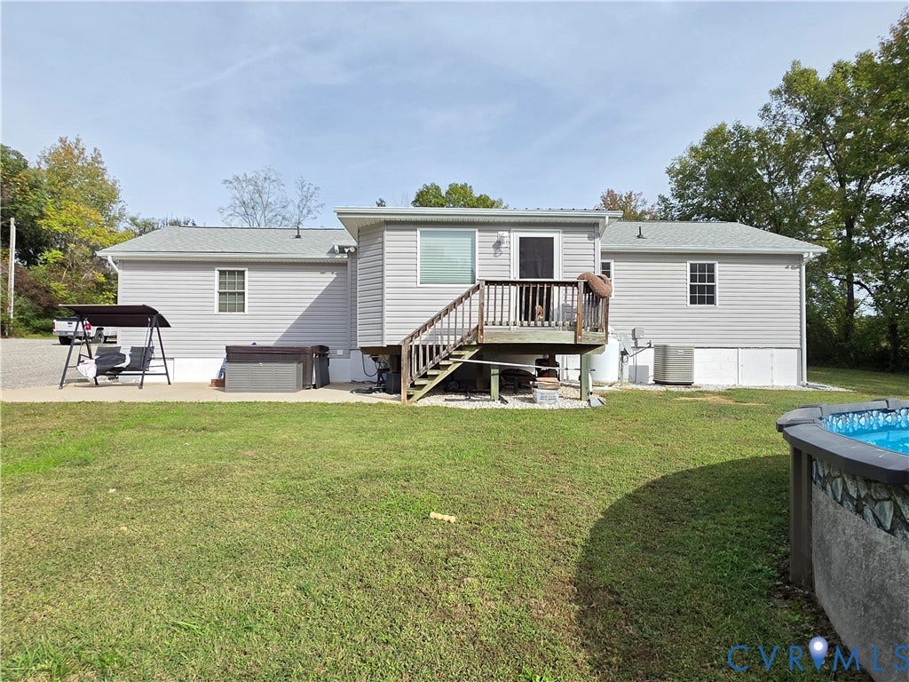 Gray siding exterior with a multi-level deck, above-ground pool, and a gravel parking area