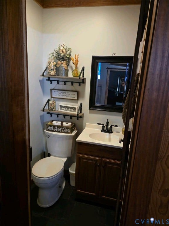 Compact bathroom featuring a dark wood-finish vanity with a white countertop and basin, dark-finish faucet, and a wall-mounted mirror