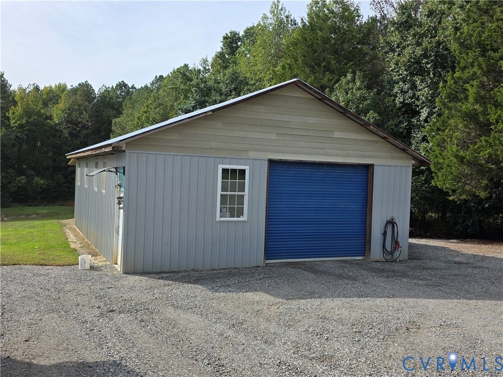 Metal-sided outbuilding with an asphalt shingle roof and a blue roll-up door