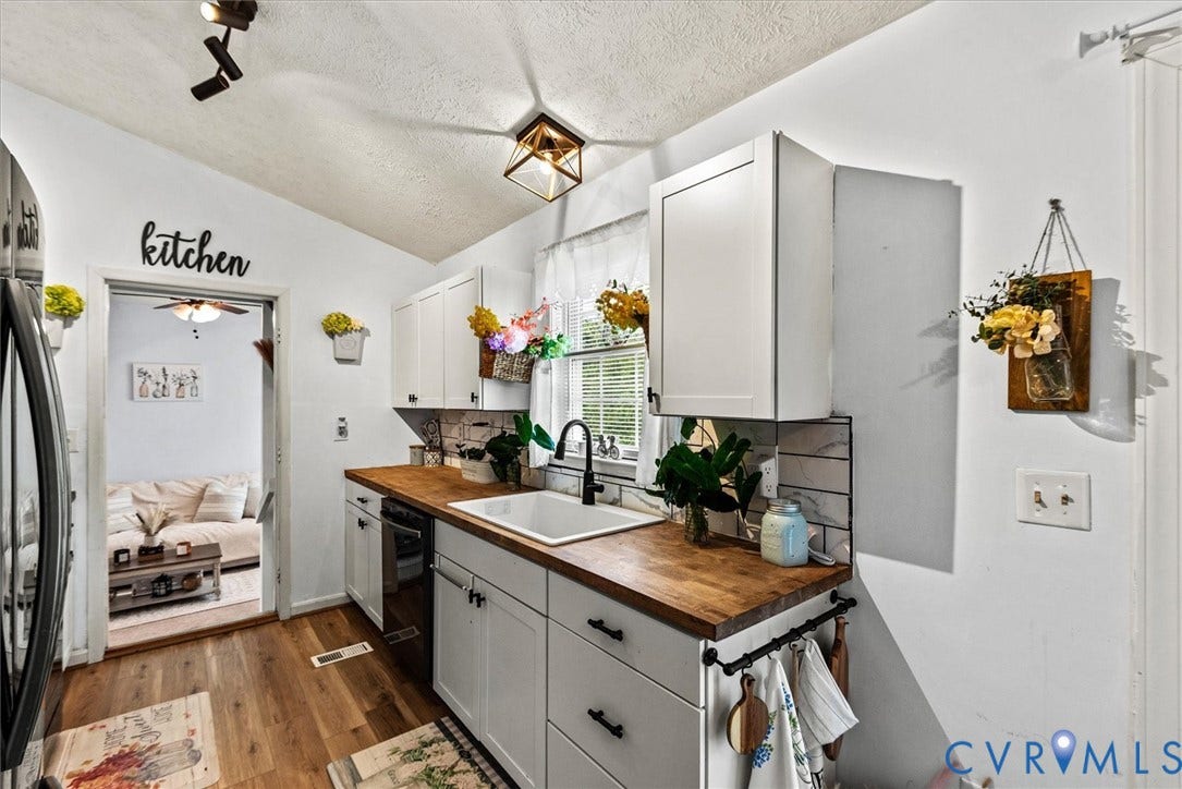 2421 Pittston Road, Ruffin's Pond, Fredericksburg, VA 22408 White shaker cabinetry with black hardware, wood-finish countertops, subway tile backsplash, and wood-finish flooring