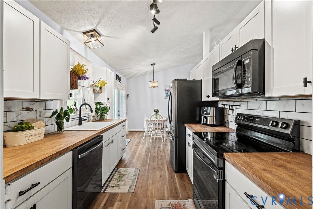 2421 Pittston Road, Ruffin's Pond, Fredericksburg, VA 22408 White shaker-style cabinetry with matte black hardware, wood-finish countertops, subway tile backsplash, and wood-finish flooring