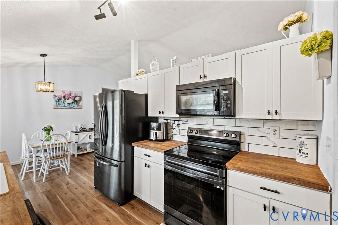 2421 Pittston Road, Ruffin's Pond, Fredericksburg, VA 22408 Wood-finish flooring, white cabinetry with dark hardware, butcher block countertops, white subway tile backsplash, and stainless steel appliances