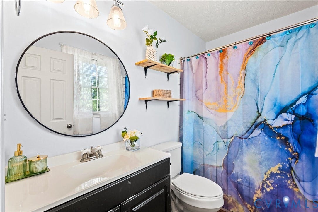 2421 Pittston Road, Ruffin's Pond, Fredericksburg, VA 22408 Vanity with an integrated sink and chrome faucet, round wall mirror, and dual wall-mounted shelves