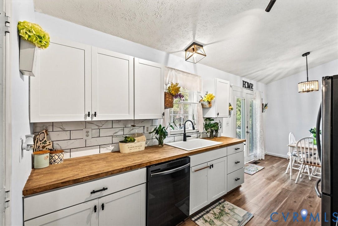 2421 Pittston Road, Ruffin's Pond, Fredericksburg, VA 22408 White shaker-style cabinetry with matte black hardware, wood-finish countertops, white subway tile backsplash, and a black built-in dishwasher