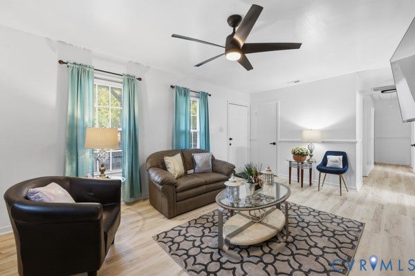 4647 Twelveoaks Road, Midlothian, VA 23112 Living area featuring light-toned wood-finish flooring, white chair rail molding, multi-pane windows, and a modern ceiling fan with integrated lighting