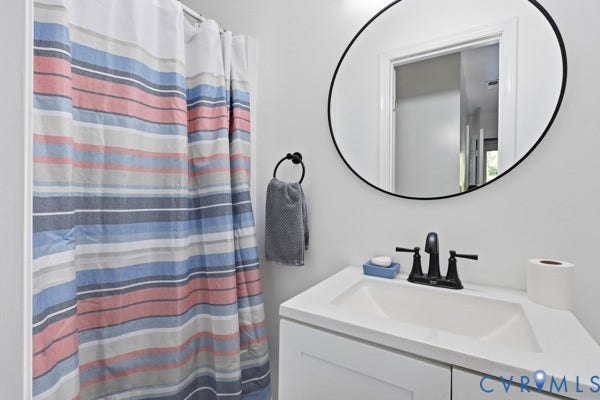 4647 Twelveoaks Road, Midlothian, VA 23112 White vanity with a rectangular sink, matte black faucet, and circular wall-mounted mirror with a black frame