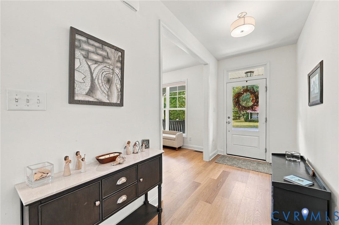 Entryway featuring light wood-finish flooring, white walls, and a white paneled door with glass inserts and transom