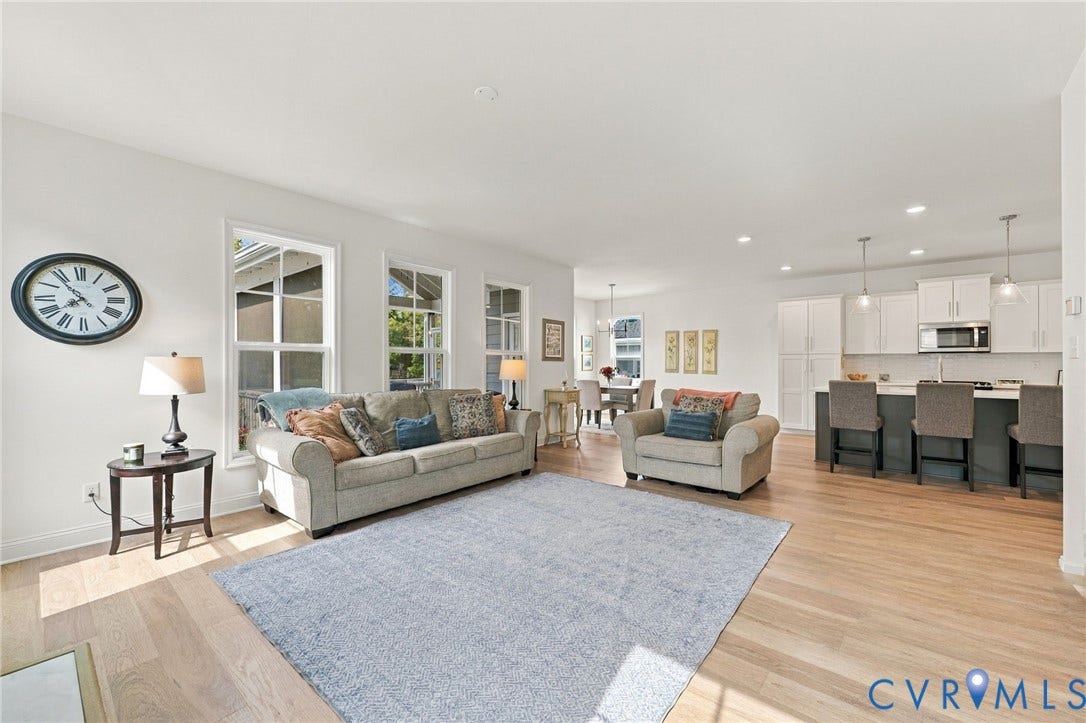 Light wood-finish flooring throughout, multiple windows with white trim, open-concept layout, recessed lighting, and a kitchen island with pendant lighting