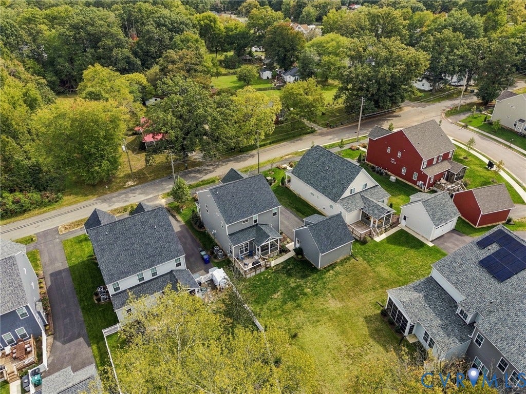 Aerial perspective showcasing multiple properties, each featuring a pitched roof, individual driveways, and private yard space