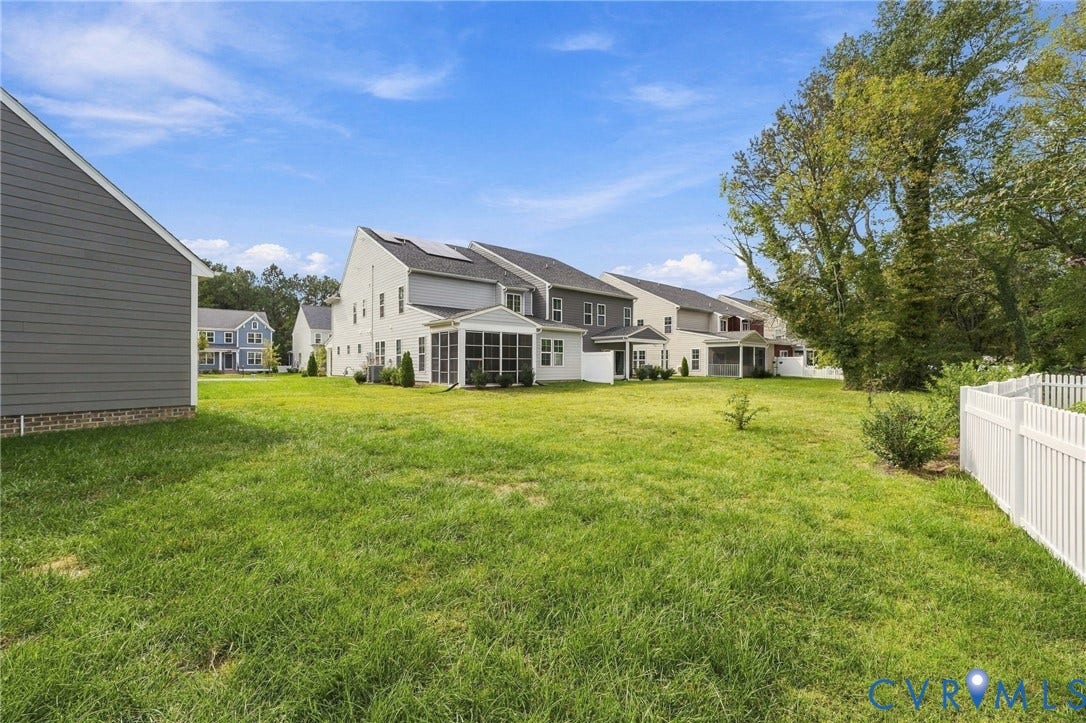 Expansive grassy yard area with a white picket fence, mature trees, and a screened-in porch on the main residence