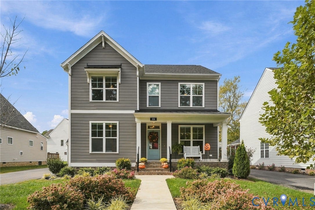 Two-story property with gray horizontal siding, prominent white trim, a covered front porch with white columns, a light blue front door, and a concrete pathway