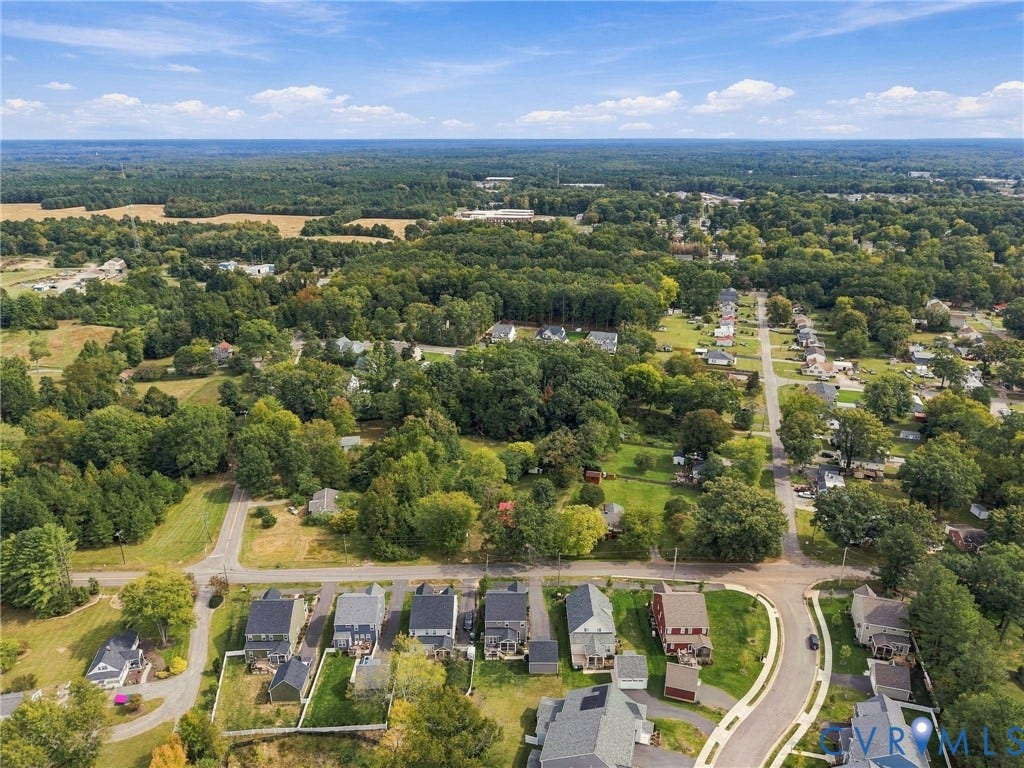 Aerial perspective showcasing residential properties and surrounding wooded areas