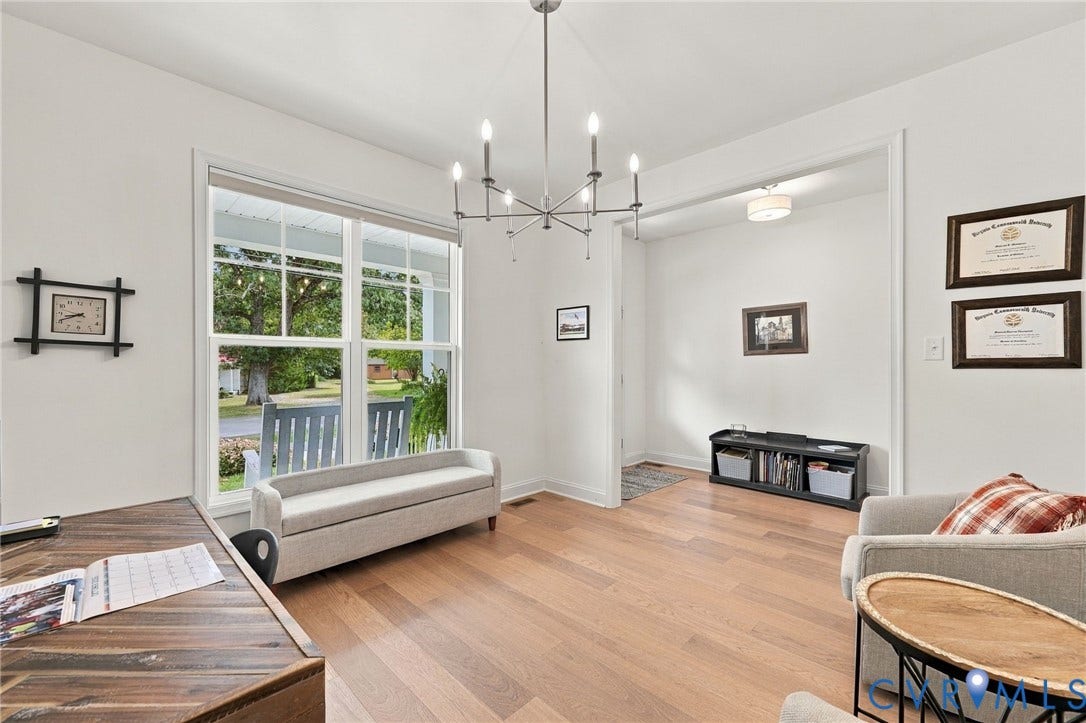 Expansive picture window, light wood-finish flooring, recessed lighting, modern chandelier, and a wide entryway