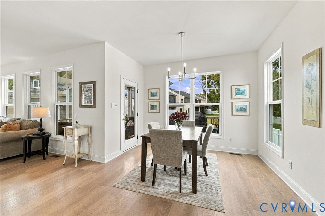 Open-concept living space with light wood-finish flooring, white trim, and multiple windows
