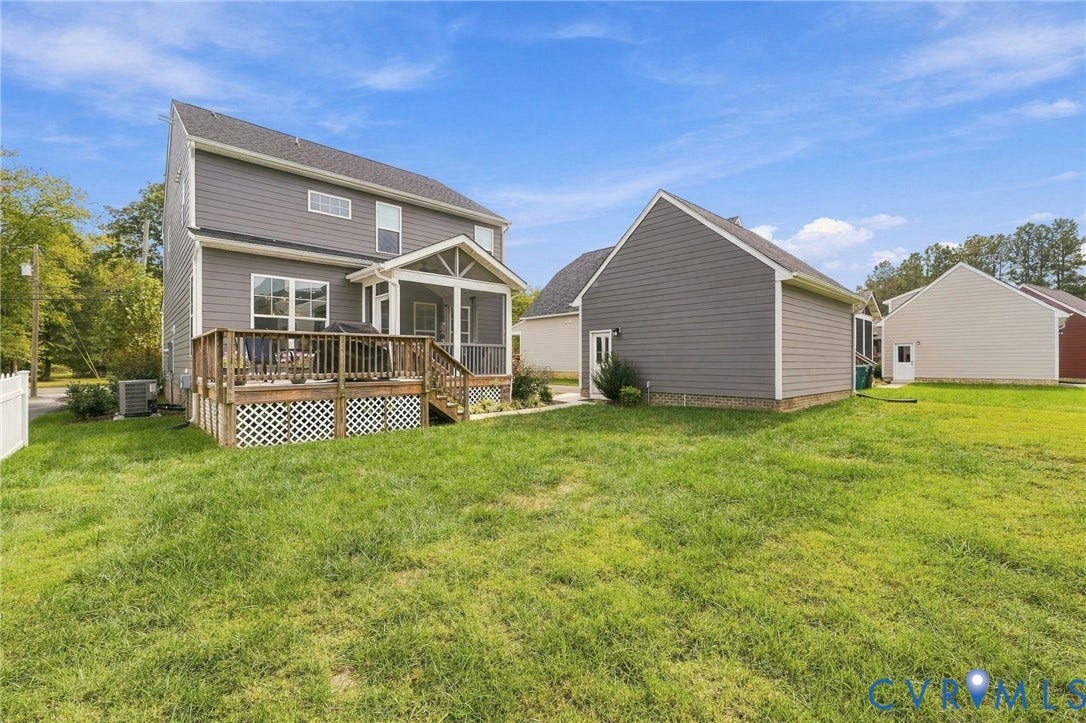 Expansive backyard with a wooden deck, screened porch, and detached garage
