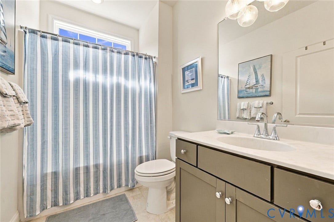 Bathroom featuring a single vanity with an integrated sink, polished chrome faucet, and a light-toned countertop