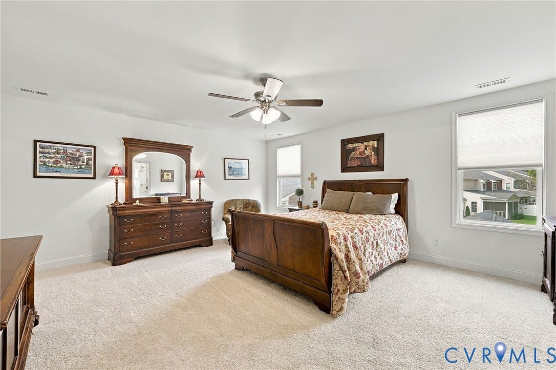 Plush carpeting, recessed window with roller shade, ceiling fan with integrated lighting, and white walls
