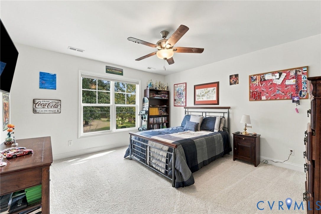 Carpeted room featuring a ceiling fan with integrated lighting, a large window, and light-toned walls