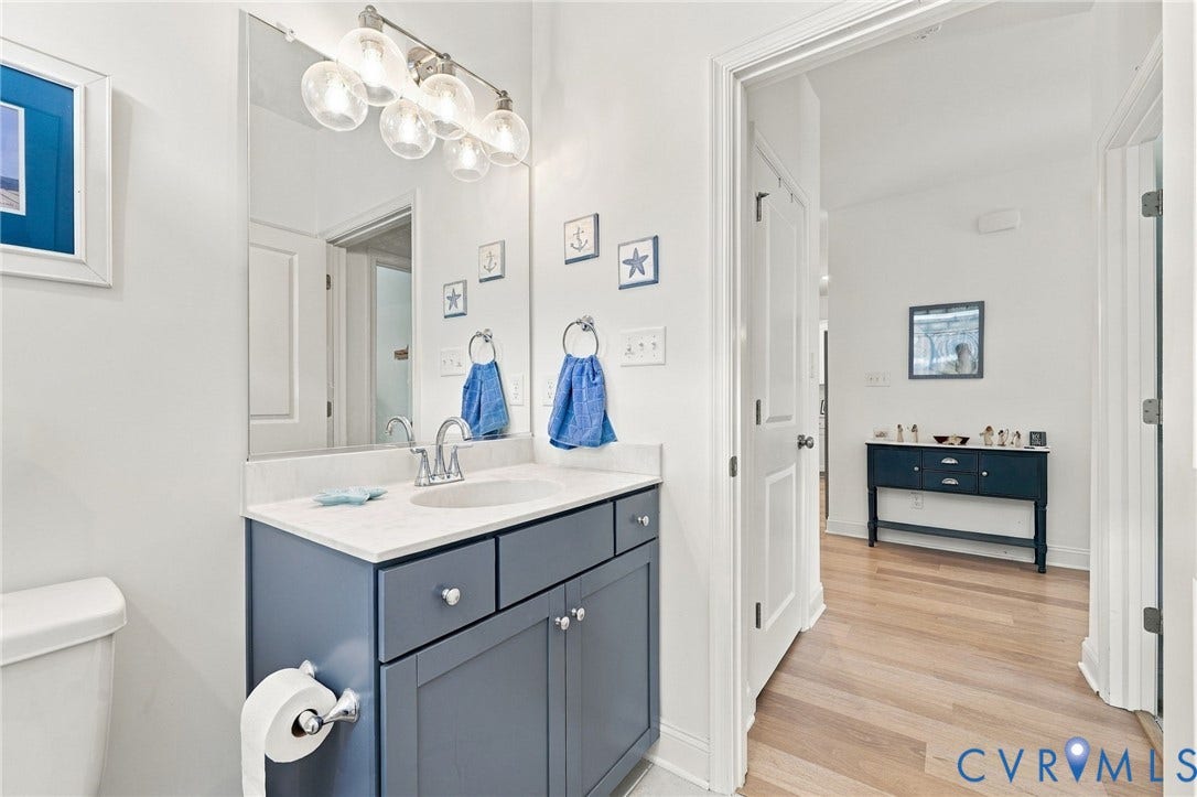 Single vanity with a light countertop, undersink cabinetry, and a wall-mounted mirror