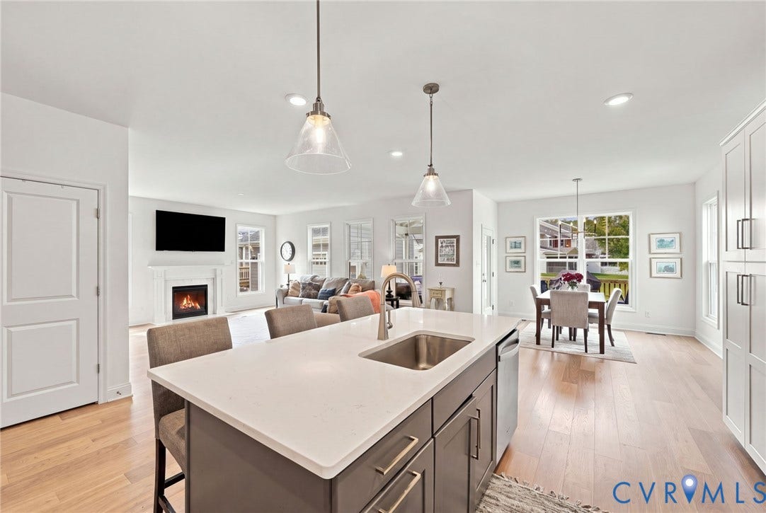 Contemporary kitchen island with a stainless steel sink, light-toned countertops, and pendant lighting