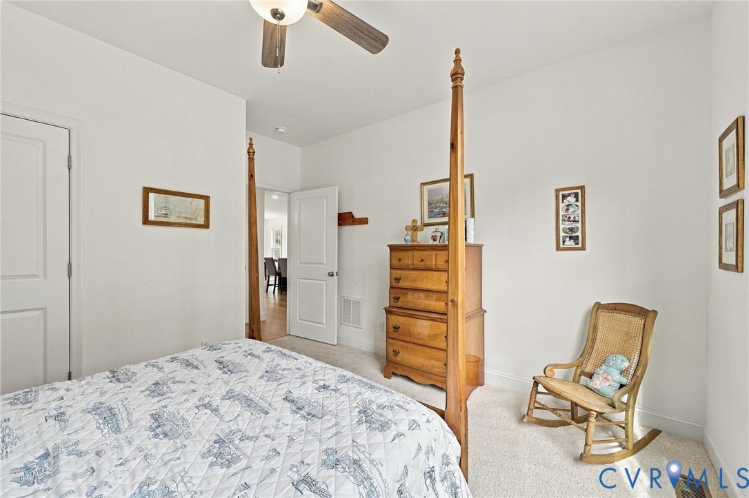 Light-toned carpet flooring, white painted walls, and a ceiling-mounted fan with light fixture