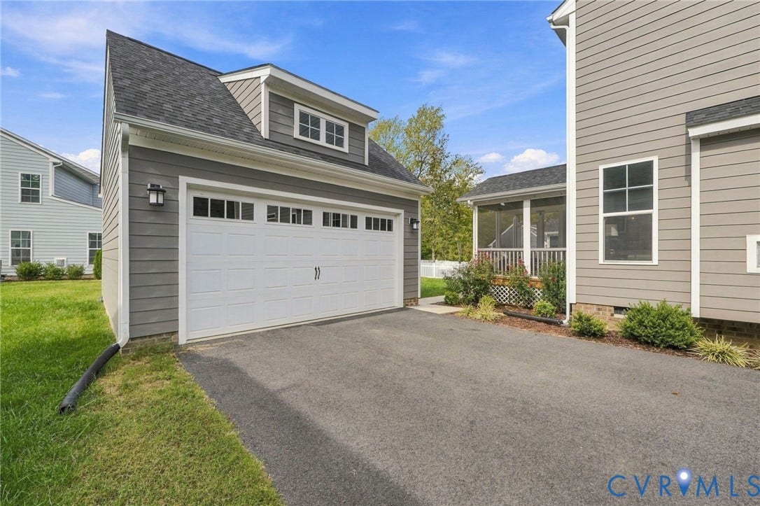 Detached two-car garage with a dormer window, an asphalt driveway, and a screened porch