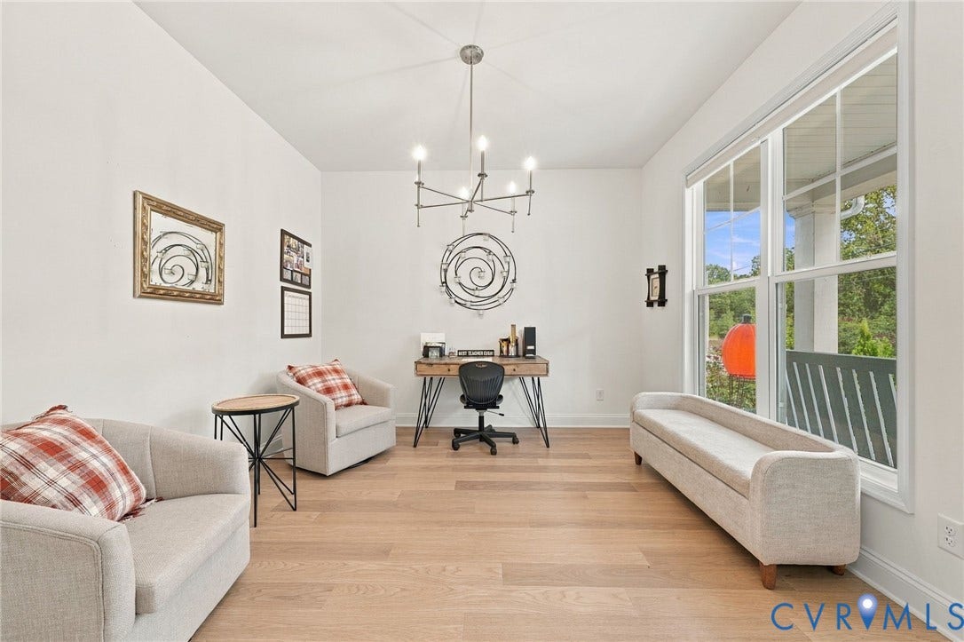 Expansive room featuring high ceilings, wood-finish flooring, a contemporary chandelier, and large multi-pane windows